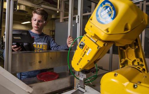 An industrial engineering student tests a robotic arm used in manufacturing.