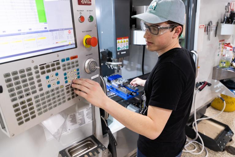 A male Kettering University student changes the settings on a machine.